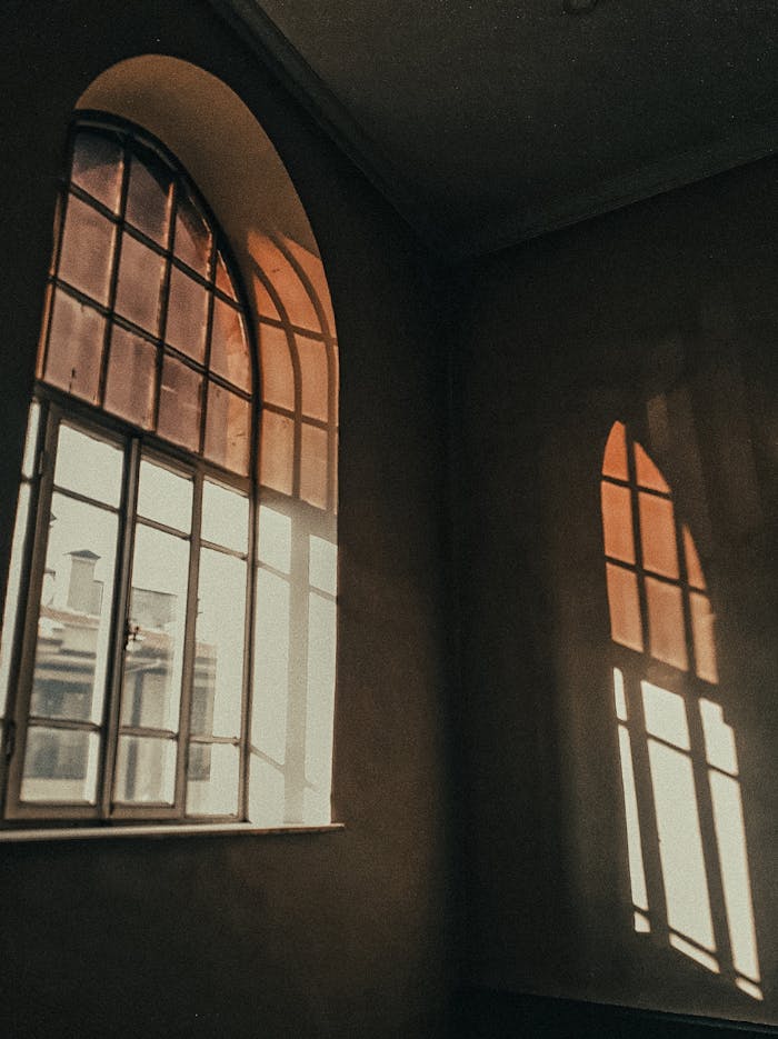Warm sunlight filtering through arched windows, casting soft shadows inside a room.