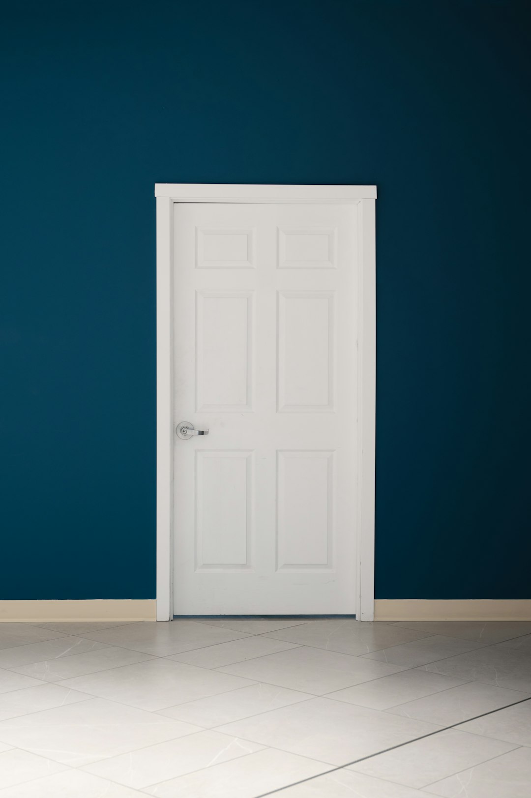 an-empty-room-with-a-white-door-and-a-blue-wall-ricdue91hwk